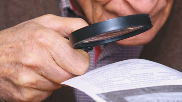 An old man looking with a magnifier